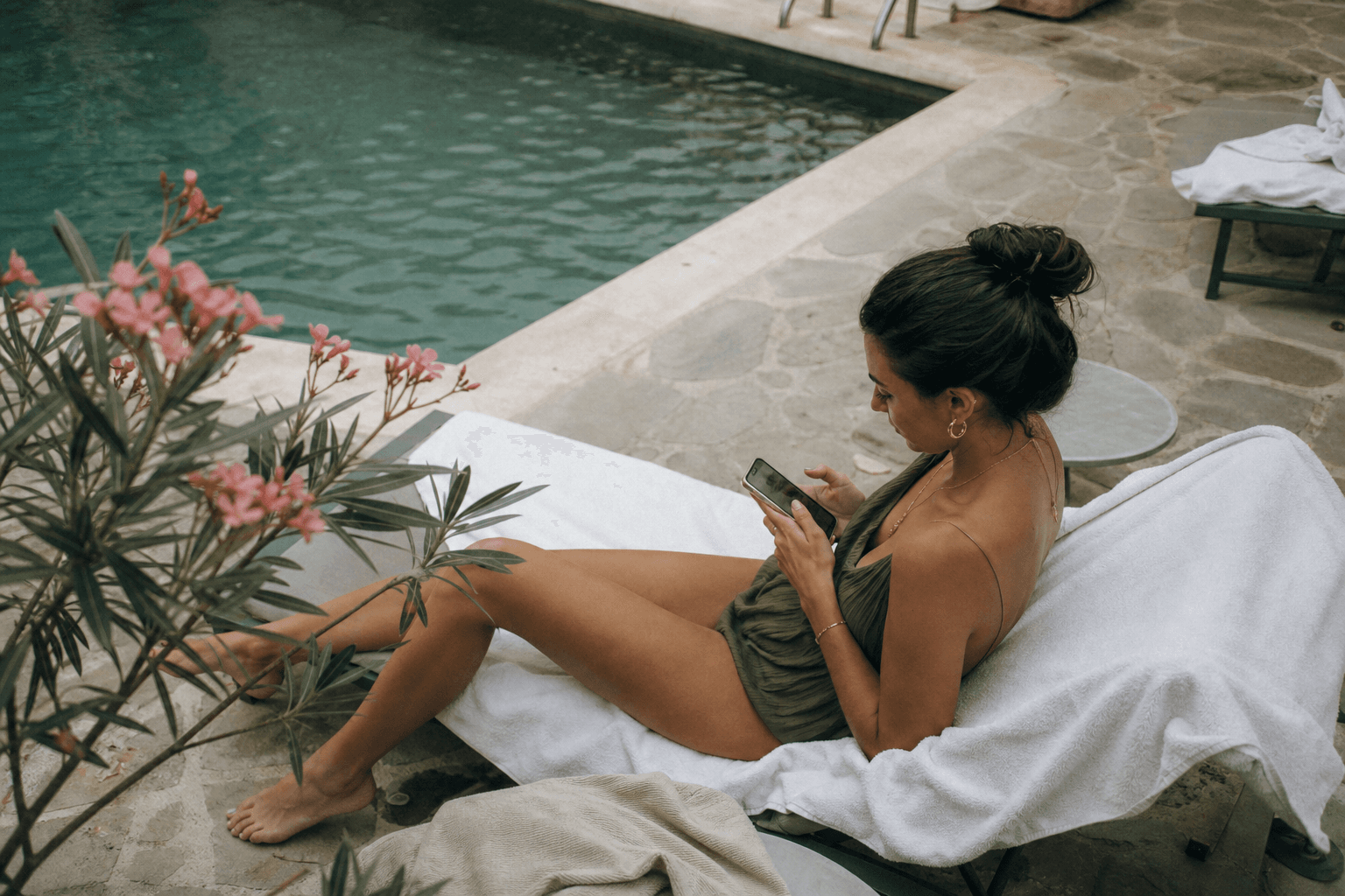 Guest by a hotel pool messaging to extend her stay